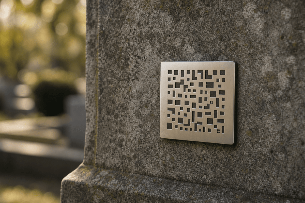 A small stainless steel memorial marker with a QR code mounted on a stone headstone outdoors in soft natural light